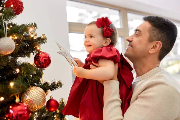 Счастливый отец и девочка украшают елку — стоковое фото