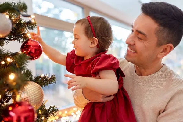 Ευτυχισμένος πατέρας και κοριτσάκι στολίζουν χριστουγεννιάτικο δέντρο — Φωτογραφία Αρχείου