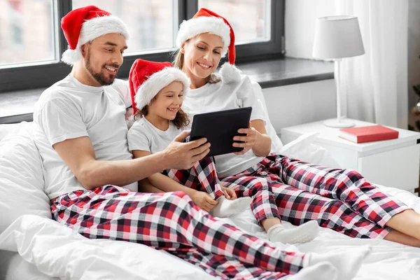 Familia feliz con la tableta PC en la cama en Navidad — Foto de Stock