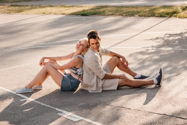 Щаслива пара сидить на баскетбольному майданчику — стокове фото