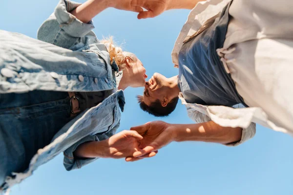 Feliz joven pareja cogida de la mano bajo el cielo azul — Foto de Stock