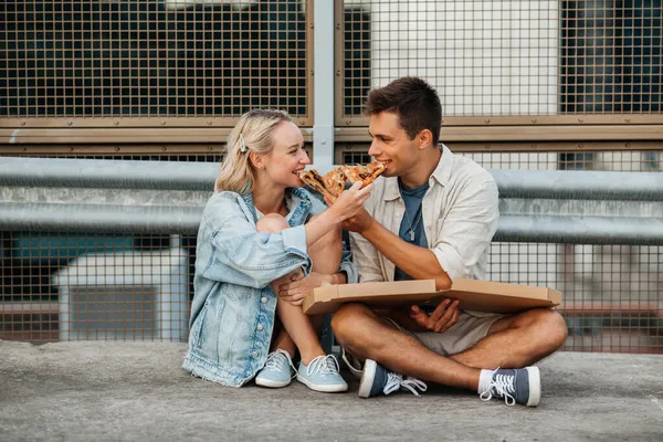 Casal feliz comer pizza no telhado da cidade estacionamento superior — Fotografia de Stock