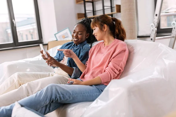 Women with smartphones moving into new home — Stock Photo, Image
