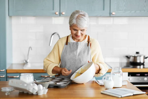 Woman putting batter into baking molds on kitchen — Stock Photo, Image