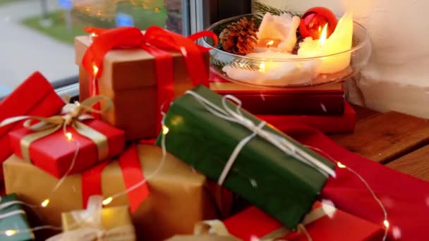 Haufen Weihnachtsgeschenke und Kerzen auf Fensterbank — Stockvideo