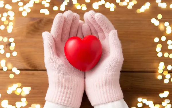 Hands in pink woollen gloves holding red heart — Stock Photo, Image