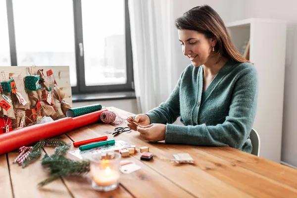 Mulher fazendo calendário de advento no Natal em casa — Fotografia de Stock