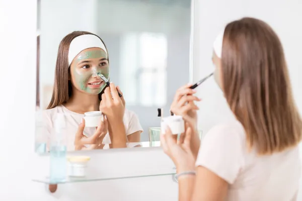 Adolescente aplicación de la máscara a la cara en el baño — Foto de Stock