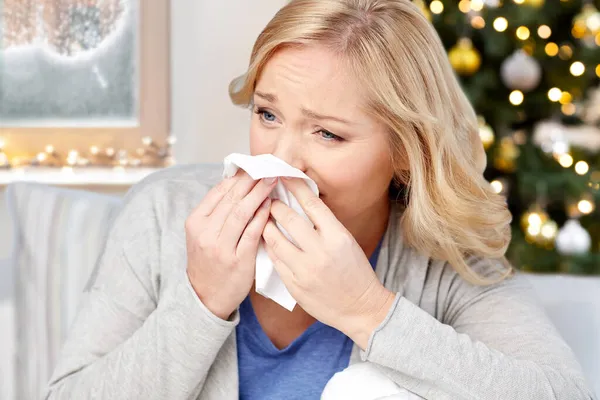 Mulher soprando nariz para tecido de papel no Natal — Fotografia de Stock