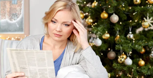 Stressed woman reading newspaper on christmas — Stock Photo, Image