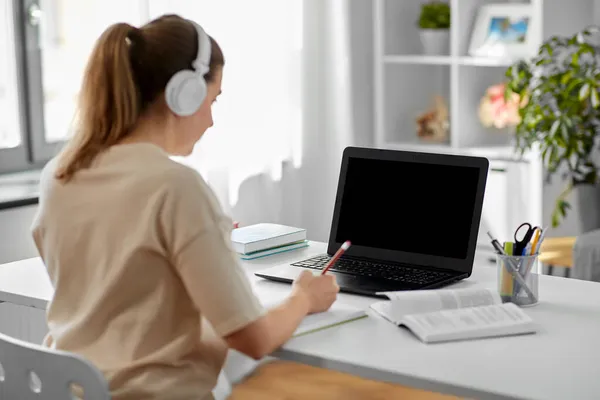 Estudiante mujer en auriculares con portátil y libro — Foto de Stock