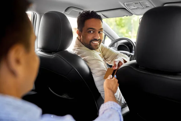 Taxichaufför som tar kreditkort från passagerare — Stockfoto