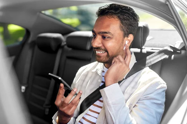 Passagerare med hörlurar och mobiltelefon i taxibil — Stockfoto