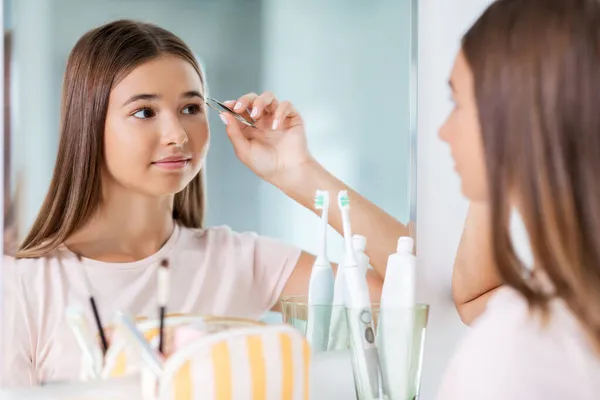 Chica adolescente pincelando su ceja en el baño —  Fotos de Stock