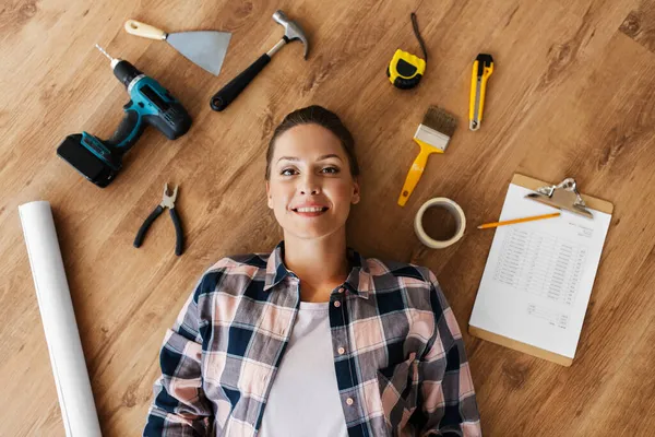 Mujer con herramientas de trabajo tumbado en el suelo de madera —  Fotos de Stock