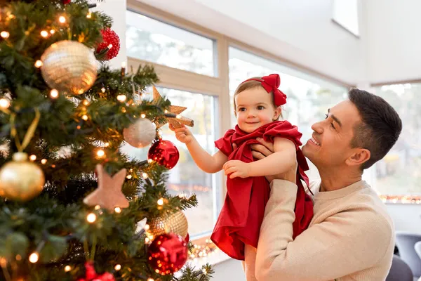 幸せな父親と赤ちゃんの女の子はクリスマスツリーを飾る — ストック写真