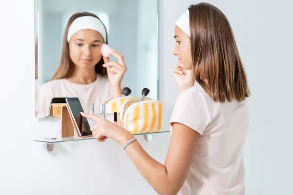 Adolescente avec smartphone en utilisant une éponge de maquillage — Photo