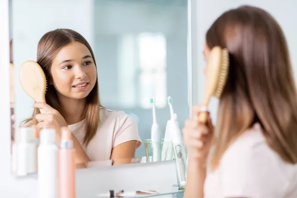 Dospívající dívka kartáčování vlasy s hřebenem v koupelně — Stock fotografie