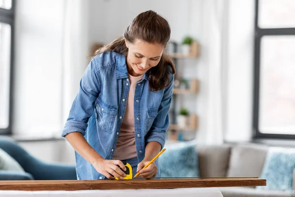 Kobieta z linijką pomiar deski drewnianej w domu — Zdjęcie stockowe