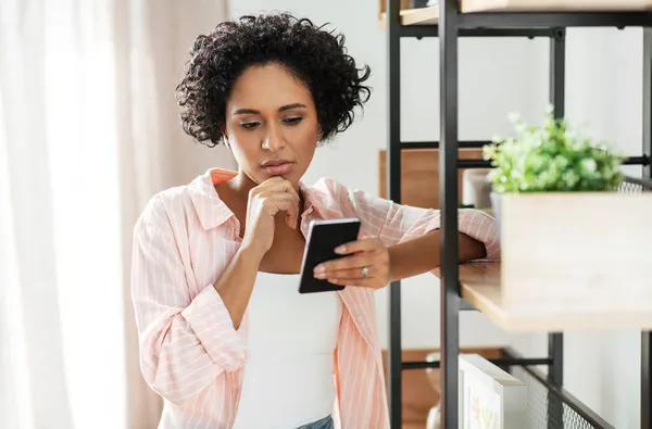 Mujer con smartphone pensando en casa — Foto de Stock