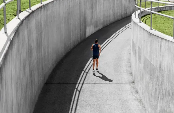 屋外のトンネルを走る若い男は — ストック写真