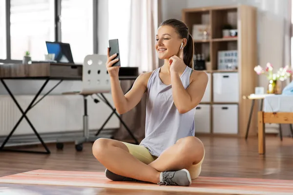 Ragazza con telefono e auricolari che si esercita a casa — Foto Stock