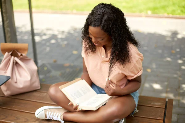 Boldog afrikai diák lány olvasás könyv a városban Stock Kép