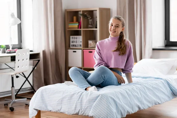 Felice sorridente ragazza seduta sul letto a casa — Foto Stock