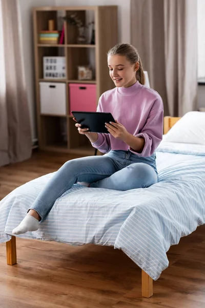 Mosolygós lány tabletta pc ül az ágyon otthon — Stock Fotó