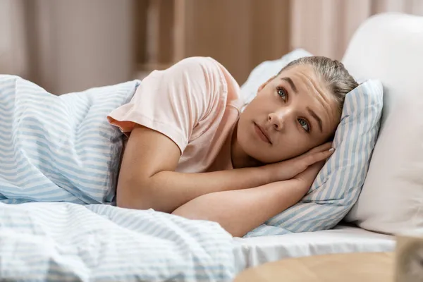 Chica despierta acostada en la cama en casa — Foto de Stock