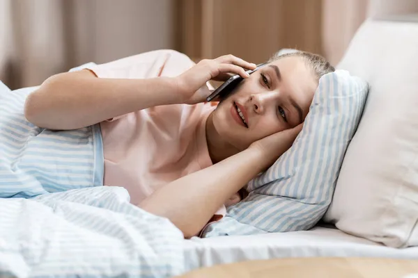 Chica feliz llamando en el teléfono inteligente en la cama en casa — Foto de Stock