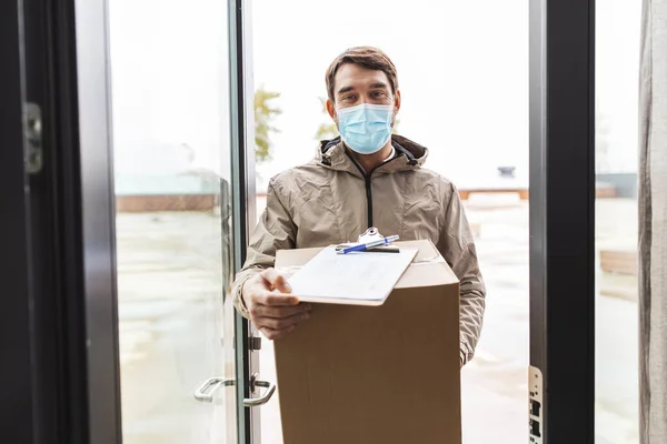 Fattorino in maschera che tiene la scatola del pacco — Foto Stock