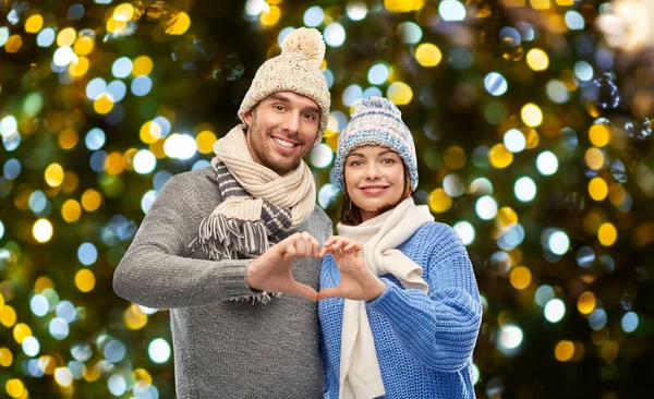 Šťastný pár v zimních šatech, které si dělají srdce — Stock fotografie