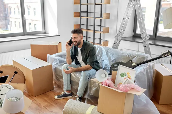 Щасливий чоловік дзвонить на смартфон, переїжджаючи в новий будинок — стокове фото