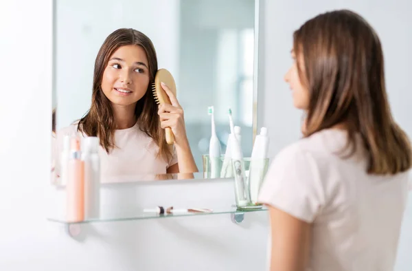 Teenager-Mädchen bürstet Haare mit Kamm im Badezimmer — Stockfoto