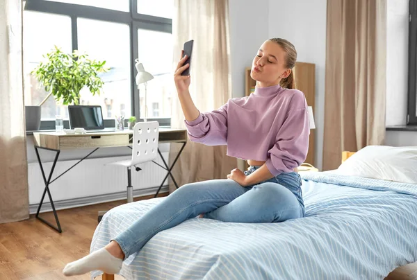 Menina feliz com smartphone levando selfie em casa — Fotografia de Stock