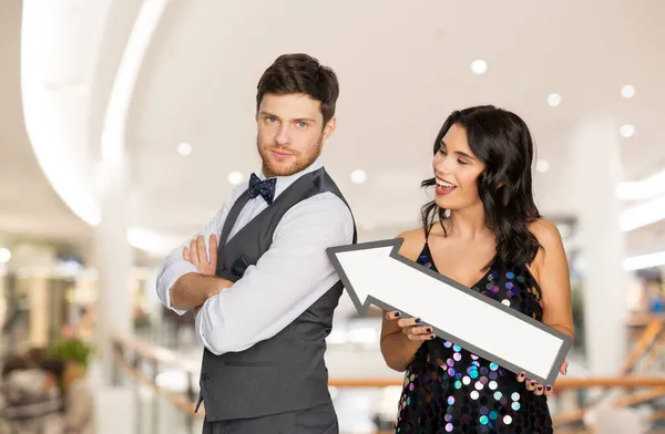 Casal feliz com grande seta sobre shopping center — Fotografia de Stock