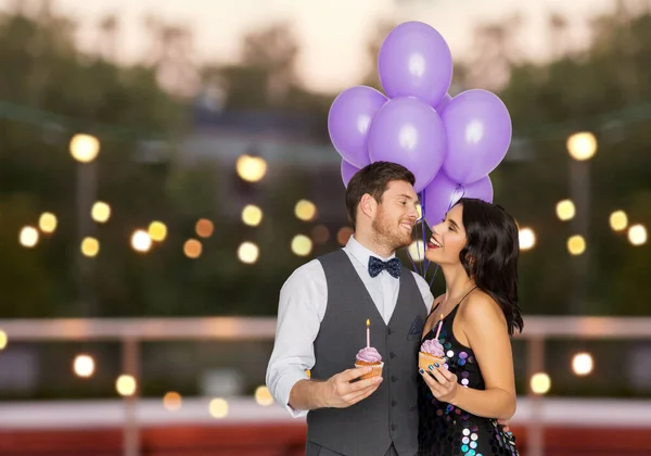 Lyckliga par med ballonger och cupcakes på fest — Stockfoto