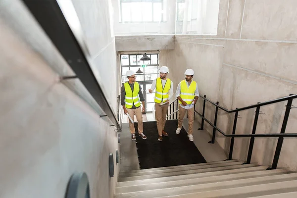 Architekten mit Helmen gehen im Büro die Treppe hinauf — Stockfoto