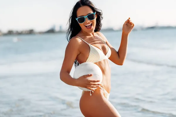 Vrouw in bikini poseren met volleybal op het strand Stockfoto