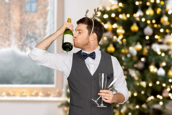 Мужчина целует бутылку шампанского на рождественской вечеринке — стоковое фото