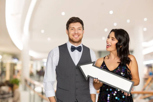 Feliz pareja con gran flecha sobre centro comercial — Foto de Stock