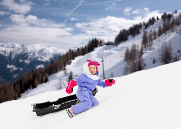 Маленька дівчинка з санчатами на сніговому пагорбі взимку — стокове фото