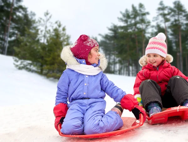 Gelukkig weinig meisjes op sleeën buiten in de winter — Stockfoto