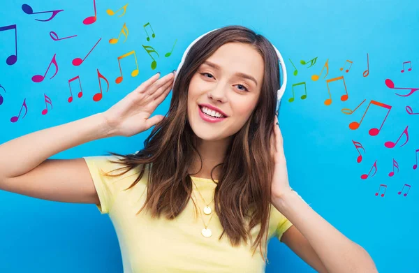 Mujer feliz con auriculares sobre notas musicales —  Fotos de Stock
