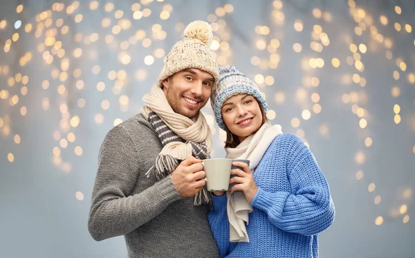 Happy couple in winter clothes with mugs — Stock Photo, Image