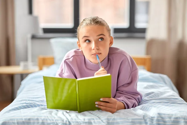 Ragazza pensante con diario sdraiato sul letto a casa — Foto Stock