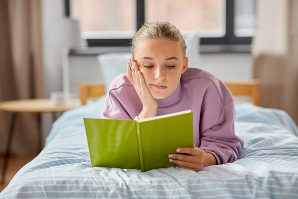 Ragazza sdraiata sul letto e leggere libro a casa — Foto Stock