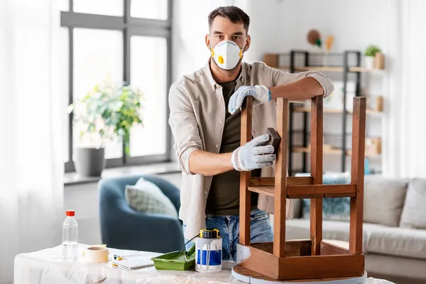 Homme dans respirateur ponçage vieille table avec éponge Photos De Stock Libres De Droits