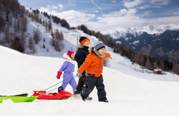 Glückliche kleine Kinder, die im Winter mit Schlitten unterwegs sind — Stockfoto